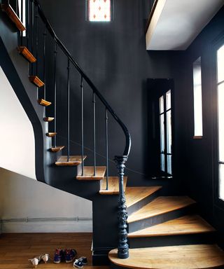 Black staircase with wooden stairs, black metal railing with black wall decor and black radiator by The Radiator Centre