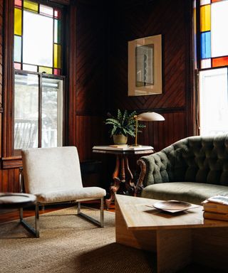 living room with wood panelling, green couch and stained glass