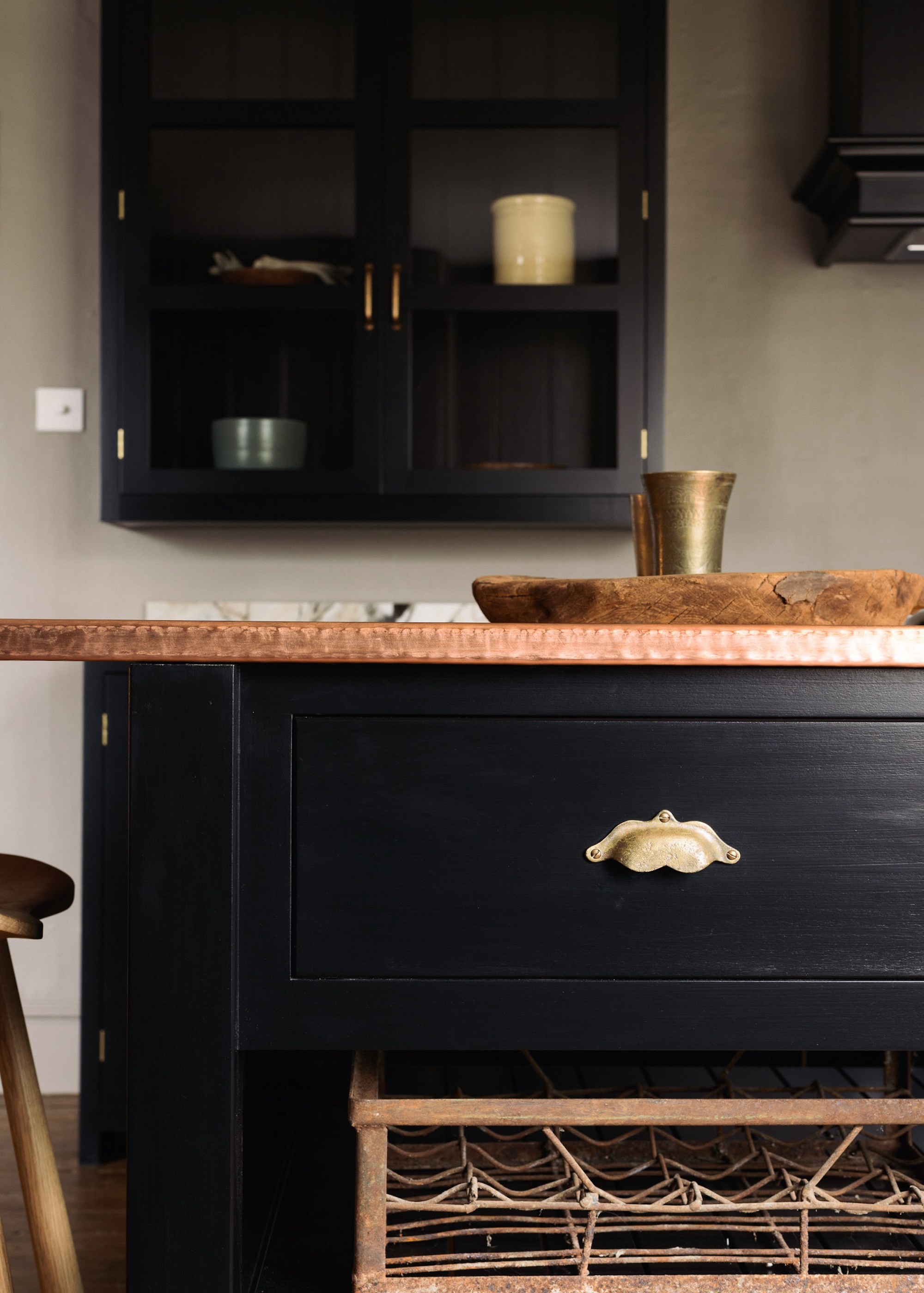 An image showing black kitchen cabinets with curved boho cup handles in aged brass