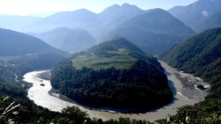 A circular river is carved into the middle of a mountainous landscape.