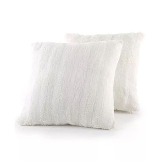 A set of two square white faux fur throw pillows leaning against one another