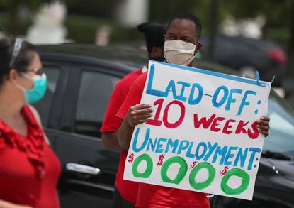 A person holds a sign about unemployment.