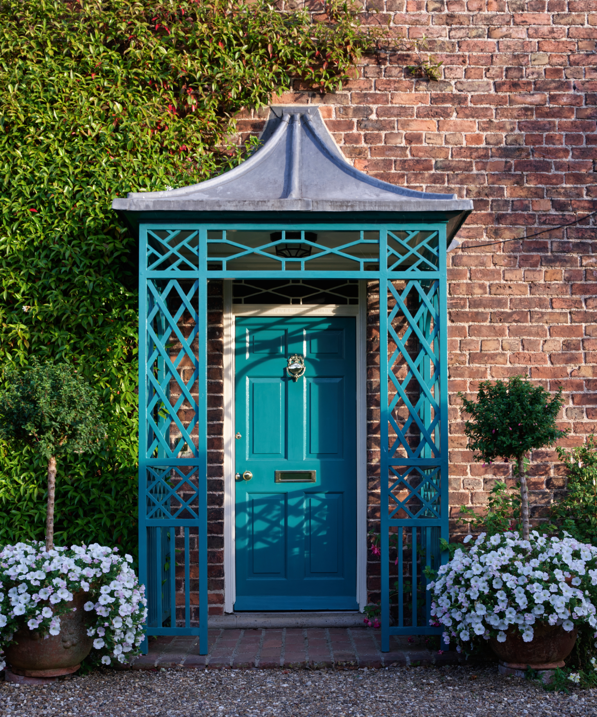 blue metal porch with intricate front and side panels topped with zinc roof