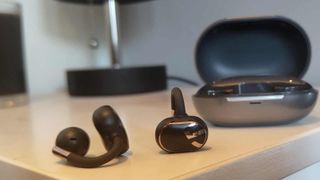 The Soundpeats Clip1 buds on a table next to the case.