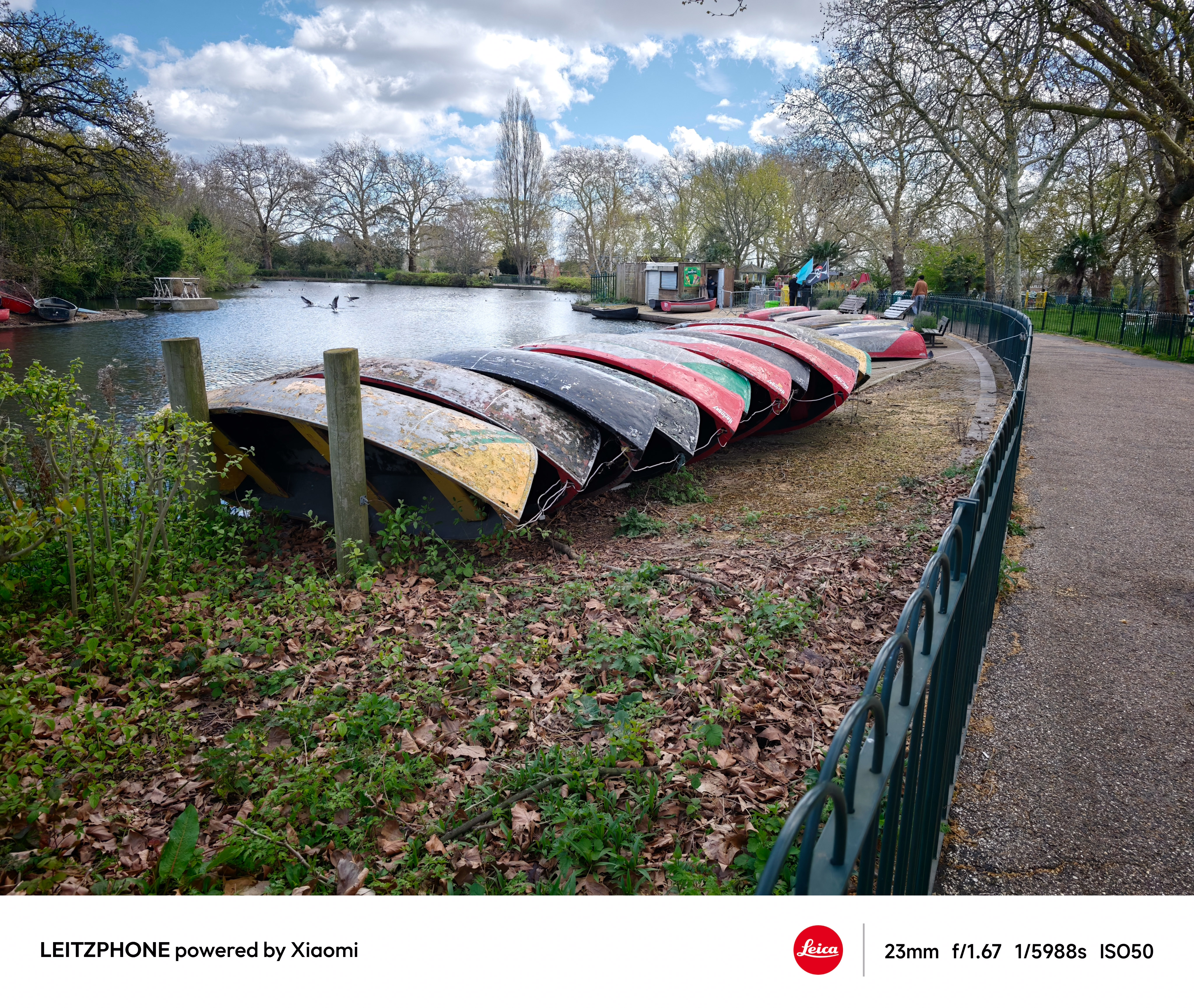 Row of colorful upside-down boats beside a lakeside path