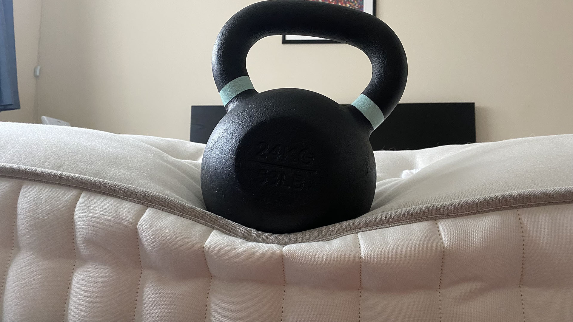 A 24kg kettlebell balanced on the bottom edge of the Simba Earth Escape mattress, demonstrating the edge support