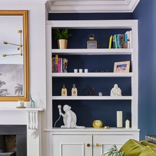 Blue and white living room with built in shelving beside fireplace and mirror