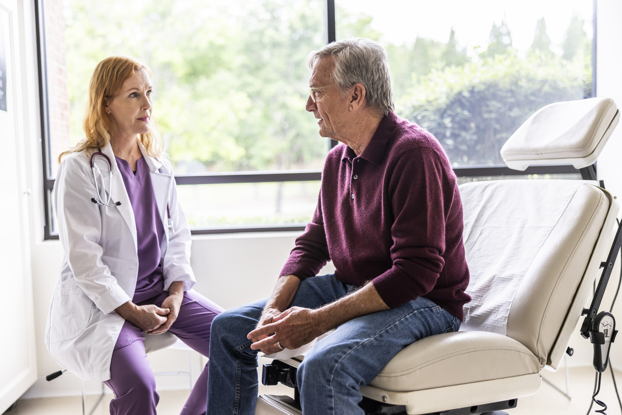 Female doctor talking with senior man in exam room
