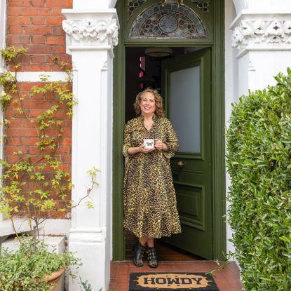 Front of house with olive green door and terracotta tiles with Lucy St George standing in the doorway