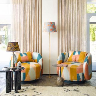 living room with two colourful upholstered armchairs table lamp and floor lamp with patterned shades