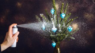 Spraying Christmas tree branches with fake snow