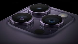 Gros plan sur le système à trois caméras de la série iPhone 14 Pro. L'appareil représenté est de la couleur Deep Purple.
