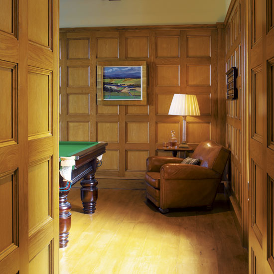 gaming room with wooden wall brown chair lamp and wooden flooring