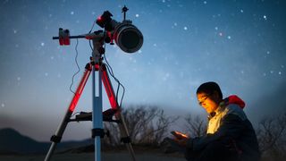 Photographer using telescope under night sky
