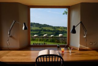 desk with book looking out of window on to incredible countryside view