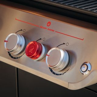 A close up of the dials on a gas grill