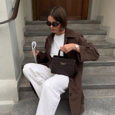 Influencer @maryljean wears white jeans with a brown jacket and chocolate brown heels.
