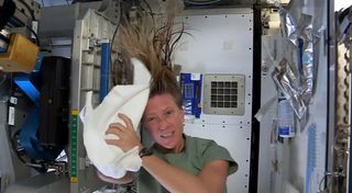 To wash her hair in space, astronaut Karen Nyberg uses a towel first to help add no-rinse shampoo to her hair, then to dry her hair in this still from a video recorded on the International Space Station and posted online on July 9, 2013. Reusing towels is vital since there is a limited supply, she says.