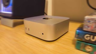 A silver Apple Mac mini (M4) on a wooden desk