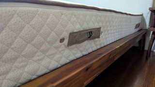 The side angle of the PlushBeds Botanical Bliss mattress, with a focus on its label