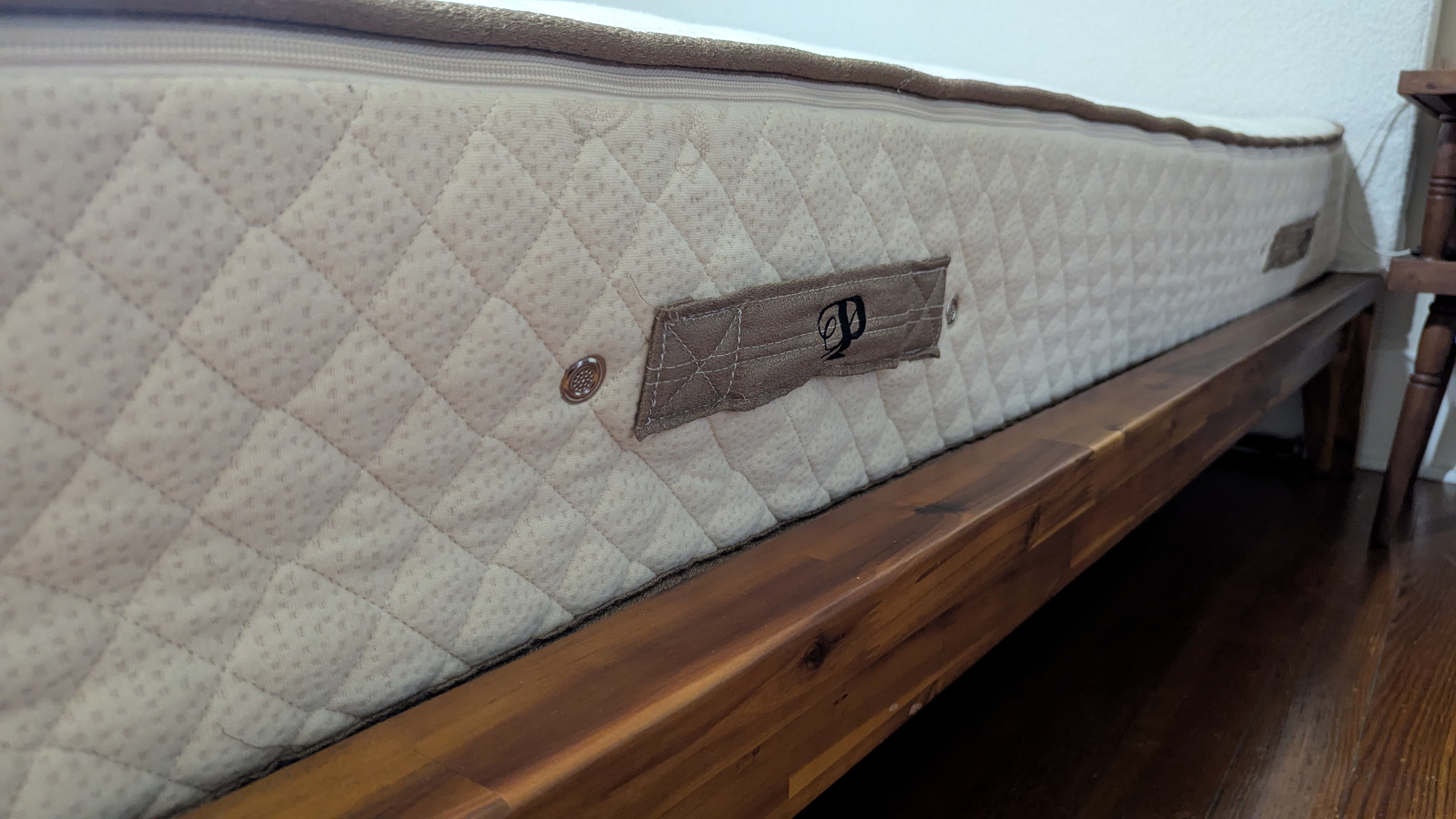 The side angle of the PlushBeds Botanical Bliss mattress, with a focus on its label