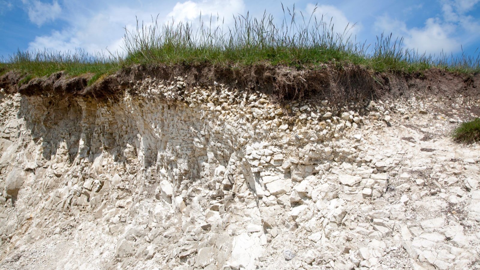 Chalk subsoil with grass on top and a blue sky in the backdrop
