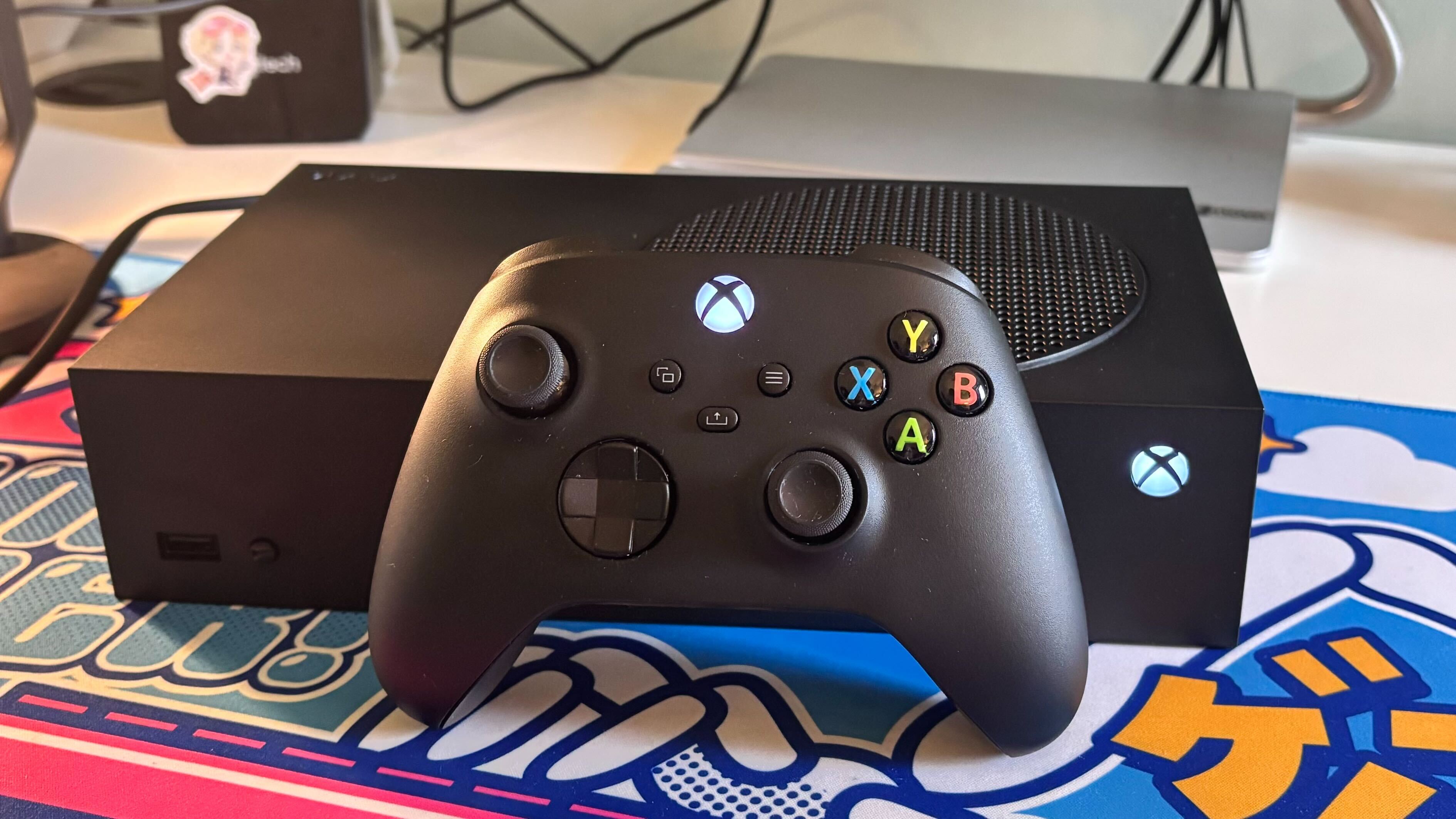 The black Xbox Series S 1TB on a colorful desk mat alongside a matching controller.