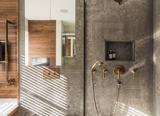 neutral bathroom with shower, patterned tiles, wooden panelling, radiator, mirror, gold shower