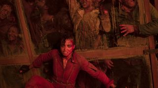 La Jade ensanglantée d'Ella Balinska est assise contre un mur alors que des zombies tentent de pénétrer dans un immeuble dans la série télévisée Resident Evil de Netflix.