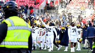 The Wolverines players celebrate as a police officer watches on in the aftermath of the Ohio State vs Michigan game in 2024