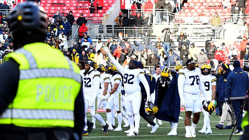 The Wolverines players celebrate as a police officer watches on in the aftermath of the Ohio State vs Michigan game in 2024