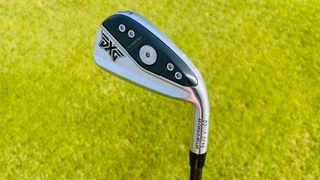 PXG 0311 P Gen6 Iron held aloft on the golf course showing off its black clubhead