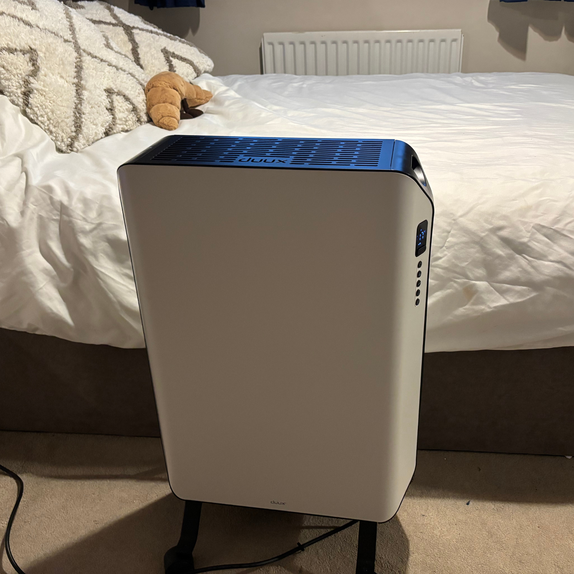 Duux Edge Oil 2000W Oil-Filled Radiator in front of a bed with white bedding