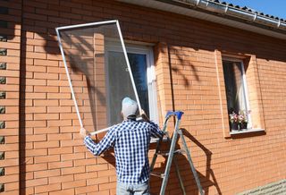 A man installing a window screen.