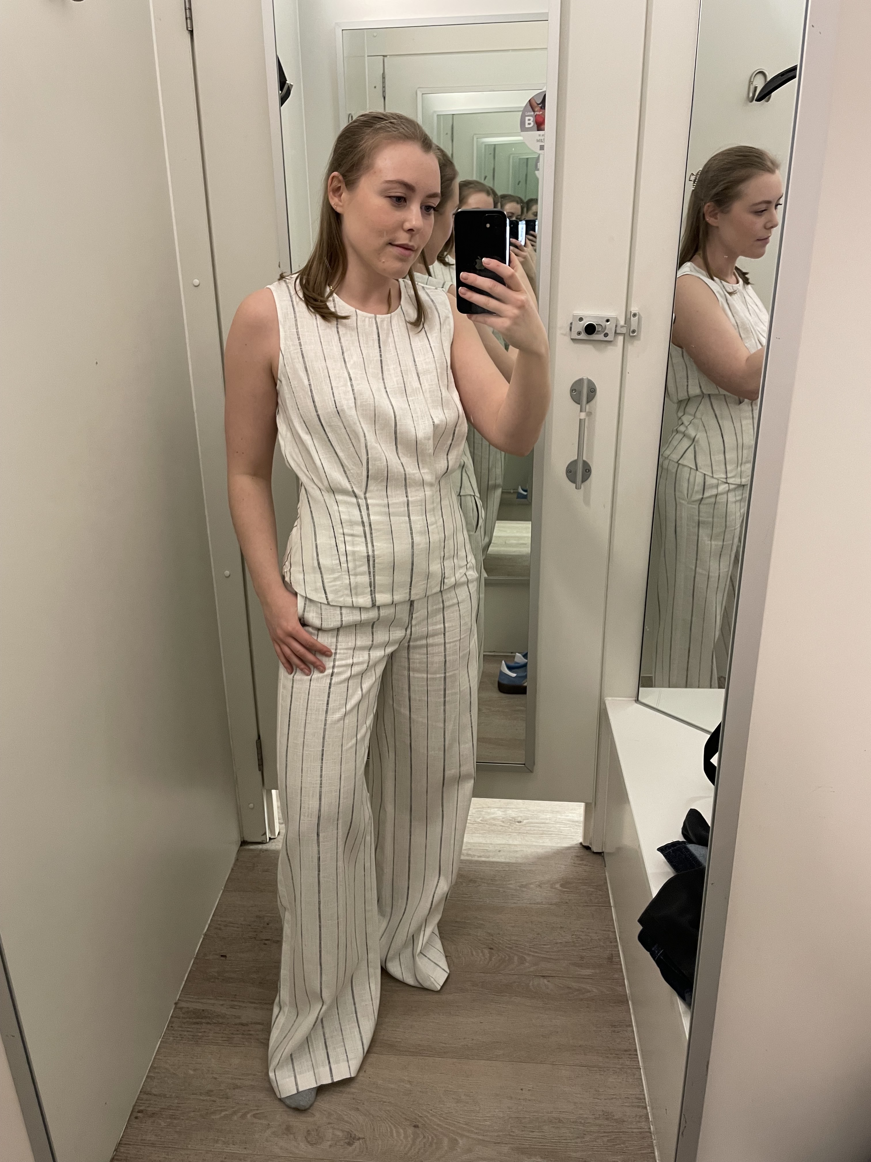 Woman in dressing rooms wears striped top and striped linen trousers