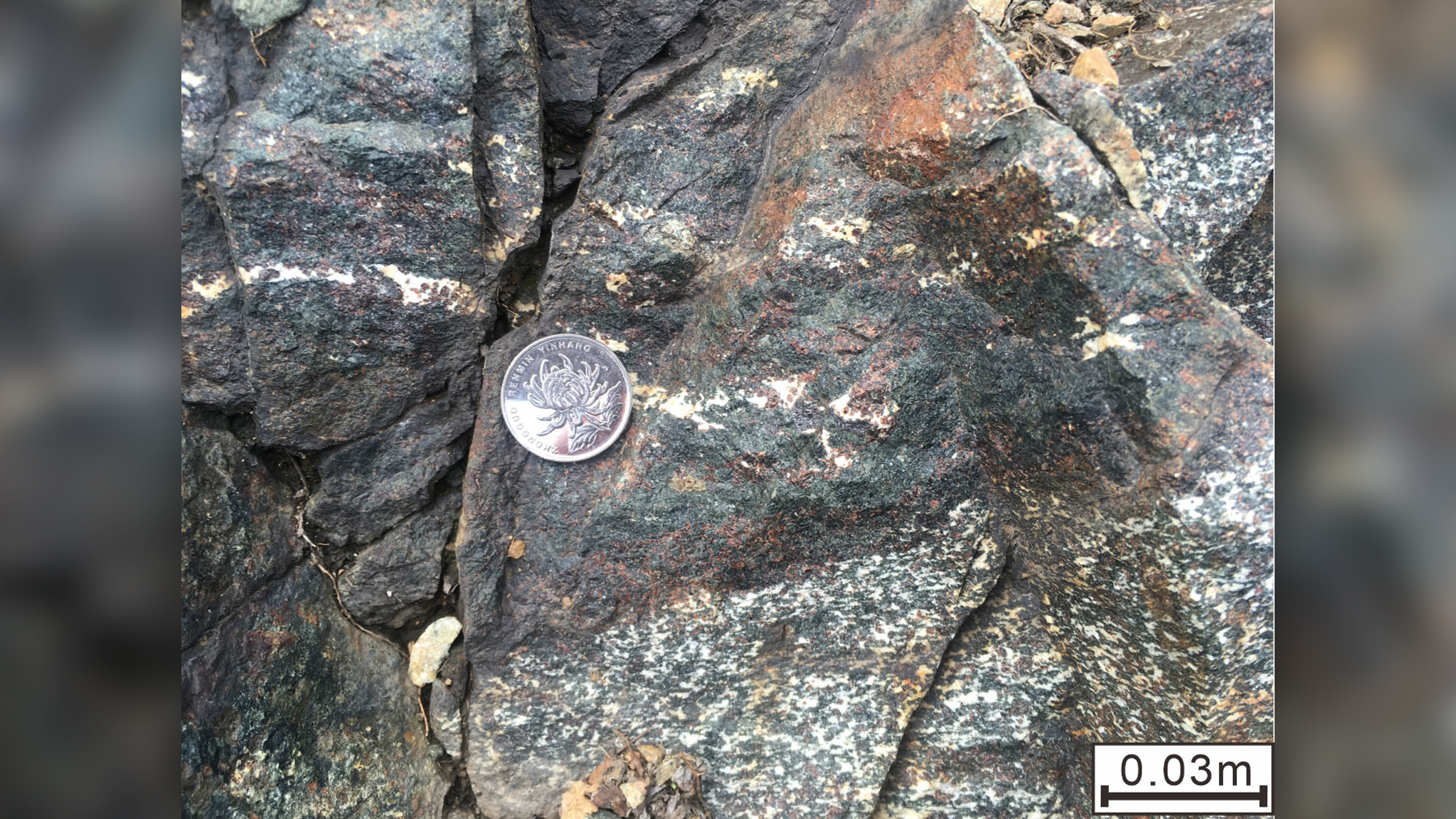 A rock formation showing eclogite (dark layer, with red garnet and green pyroxene) from the Archean eon interlayered with garnet-bearing metagabbro from Shangying, China.