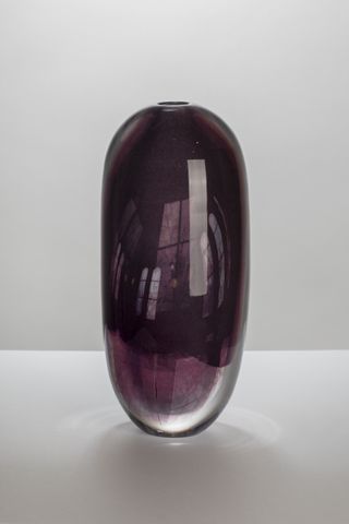 A purple oblong vase featuring reflections of the surrounding environment on its surface.