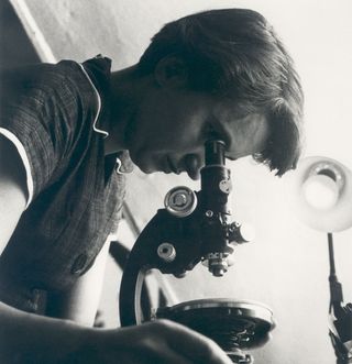 Rosalind Franklin with a microscope.