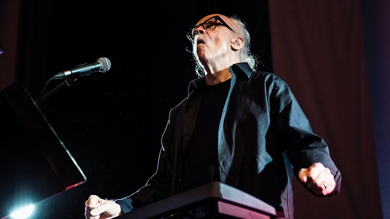 A photograph of John Carpenter on stage