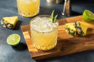A pineapple cocktail with chunks of pineapple next to it