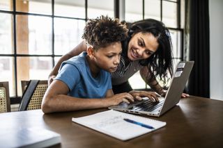 Mum and son looking at a computer and doing homework