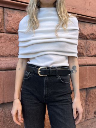 Cream top with black jeans and a black belt with gold hardware