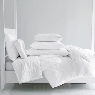 White double bed with white duvet set and pillows