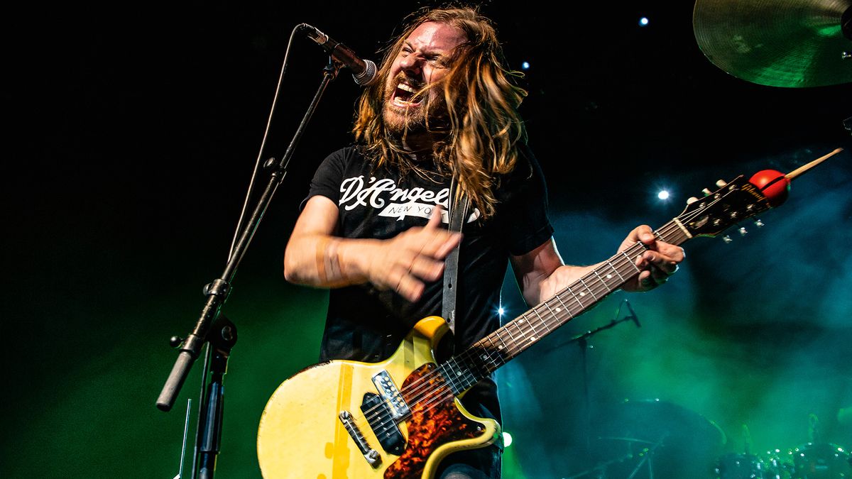 Steve Hill plays his TV Yellow Gibson Les Paul Junior Doublecut onstage, the background illluminated in green.