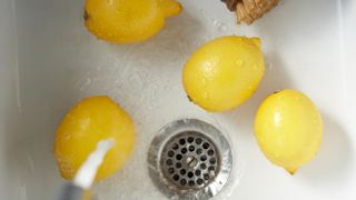 person washing lemons with water in a white sink