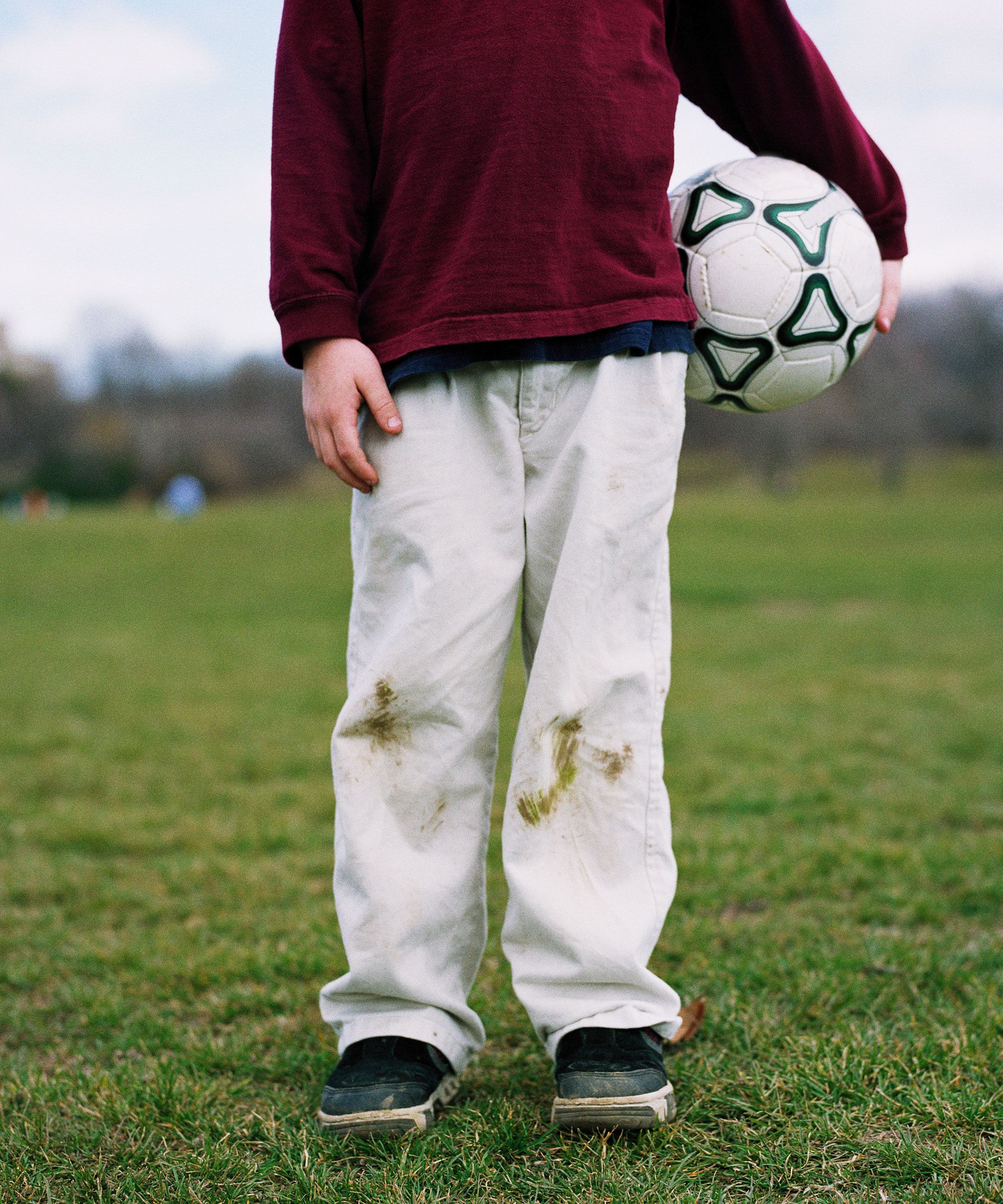 Stains of grass on white jeans on a boy with a soccer ball - GettyImages-CA33547