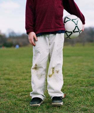grass stains on white jeans on boy with football - GettyImages-CA33547