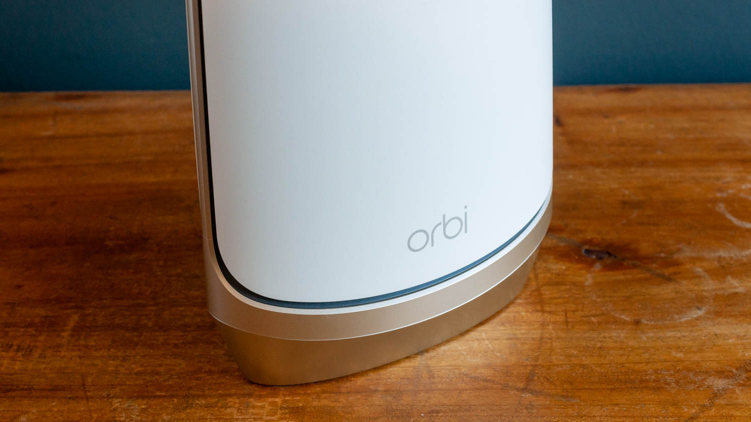 En vit Netgear Orbi WiFi 6E står placerad på ett träbord.