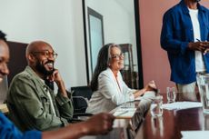 Colleagues in a modern boardroom having a casual office meeting, laughing and happy. The atmosphere is engaging and lighthearted.