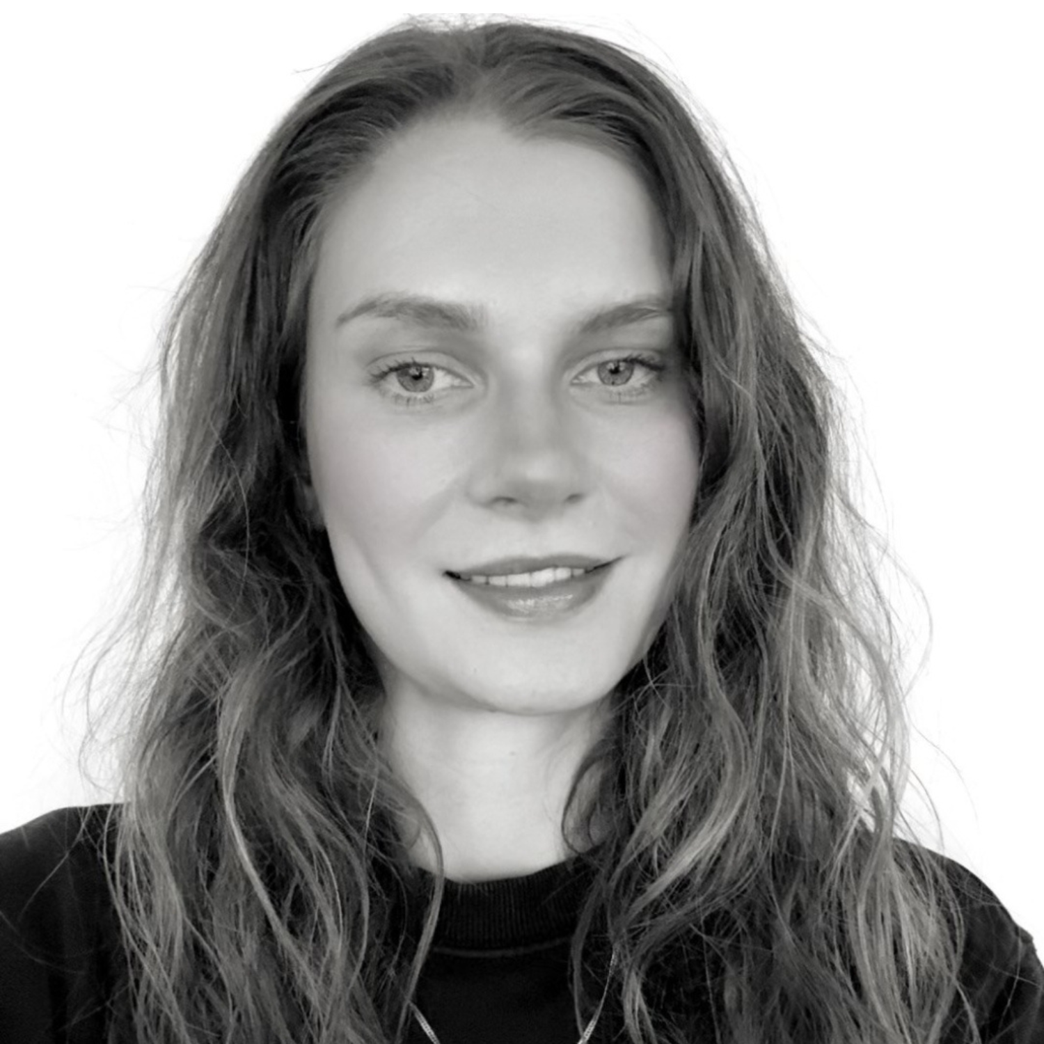 A black and white headshot of a smiling woman in a dark roundneck top